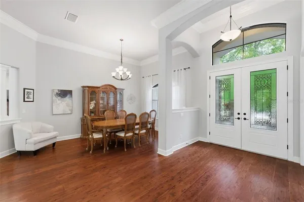 a dining room with wooden floor a chandelier a wooden table and chairs