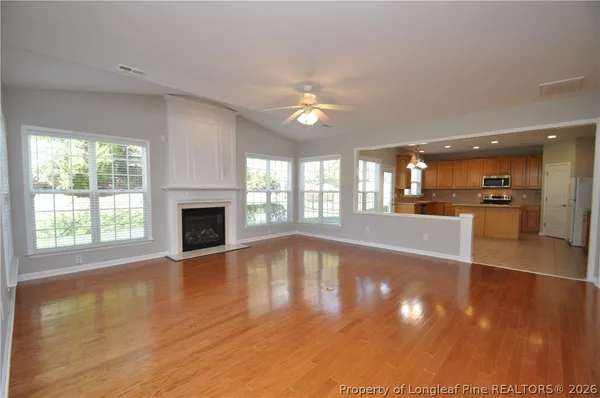 an empty room with wooden floor fireplace and windows