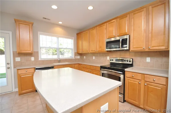 a kitchen with stainless steel appliances granite countertop a stove a sink a microwave a refrigerator and cabinets