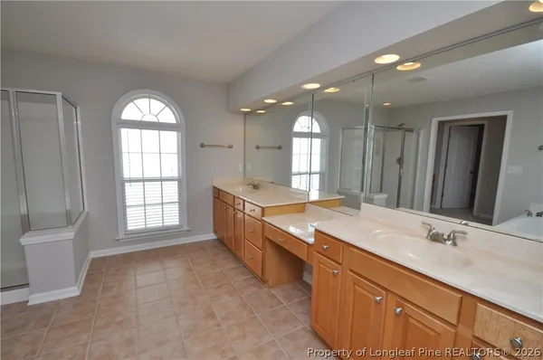 a large bathroom with a granite countertop double vanity sink a mirror and a bathtub