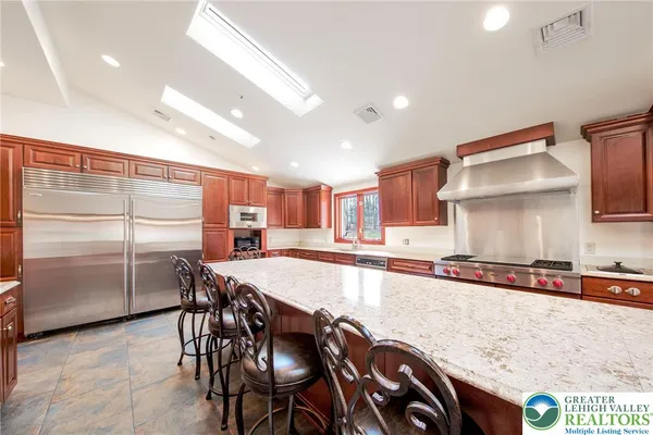 a kitchen with stainless steel appliances granite countertop a table chairs sink and cabinets
