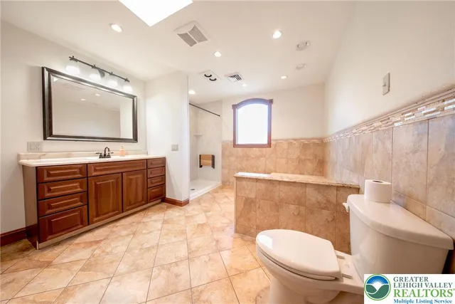 a spacious bathroom with a toilet a sink and a mirror