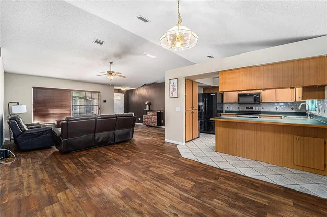 a living room with furniture kitchen and a wooden floor