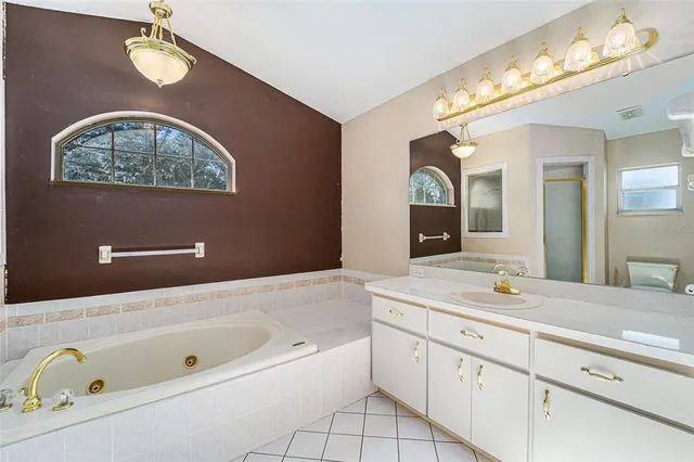 a spacious bathroom with a tub double vanity sink and a mirror