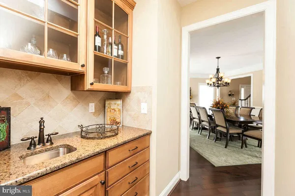 a kitchen with stainless steel appliances granite countertop a stove top oven a sink a dining table and chairs with wooden floor