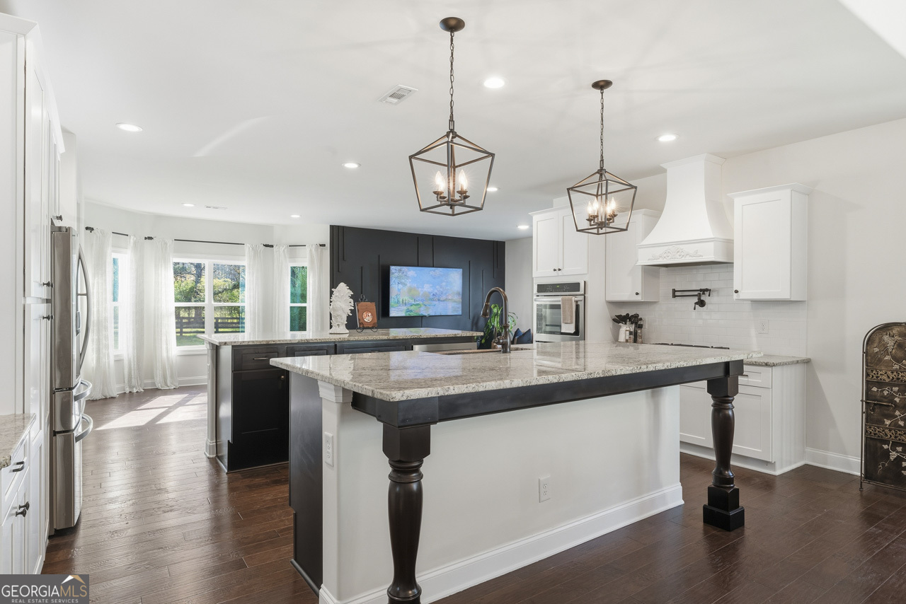 1058 Lawshe Road Senoia, GA 30276 - Photo 29 of 48 a kitchen with stainless steel appliances granite countertop a sink a stove and a wooden floors