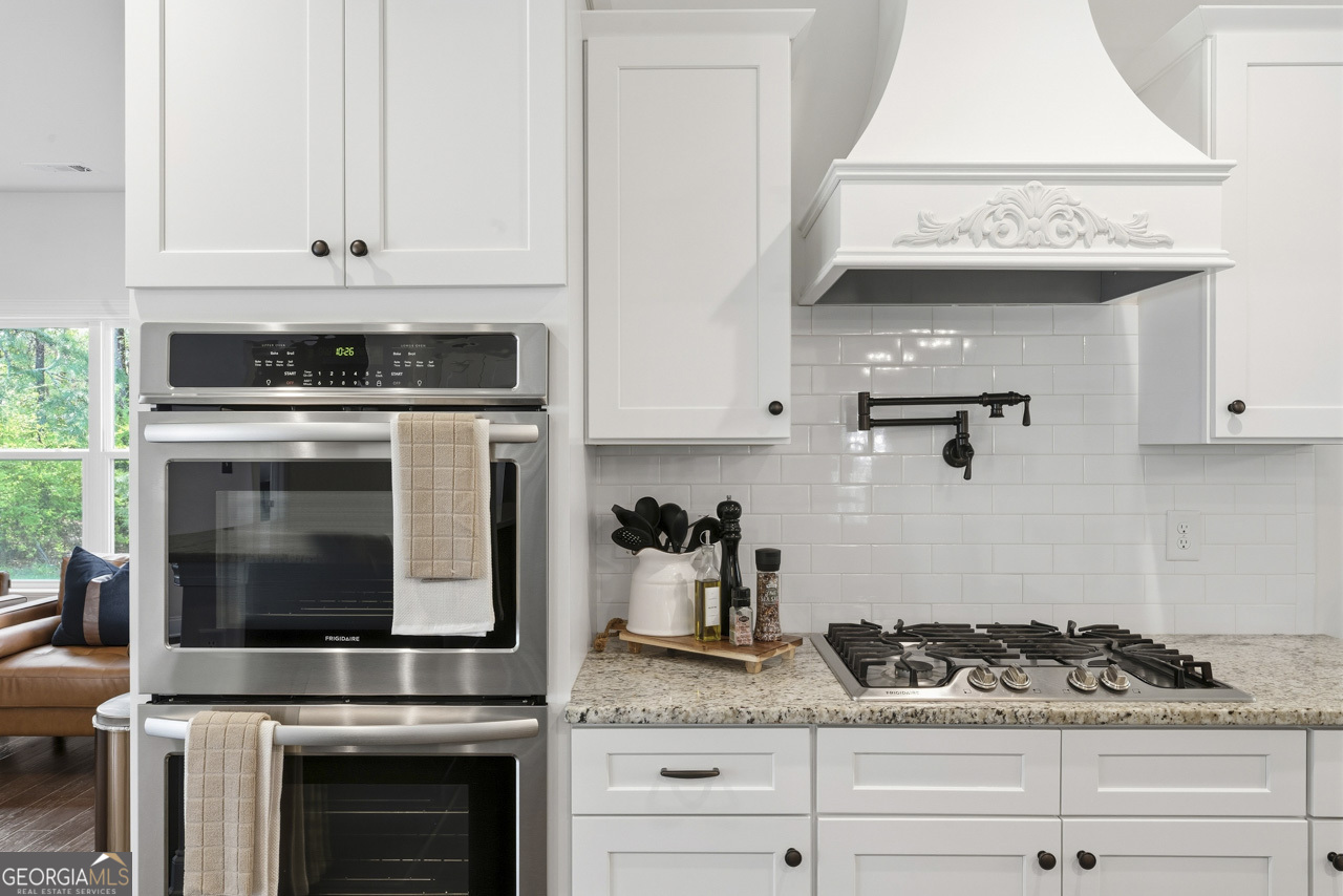 1058 Lawshe Road Senoia, GA 30276 - Photo 31 of 48 a kitchen with granite countertop white cabinets and stainless steel appliances