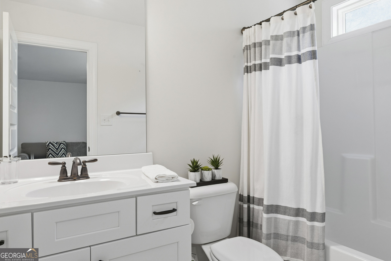 1058 Lawshe Road Senoia, GA 30276 - Photo 45 of 48 a bathroom with a sink a toilet a mirror and shower curtain