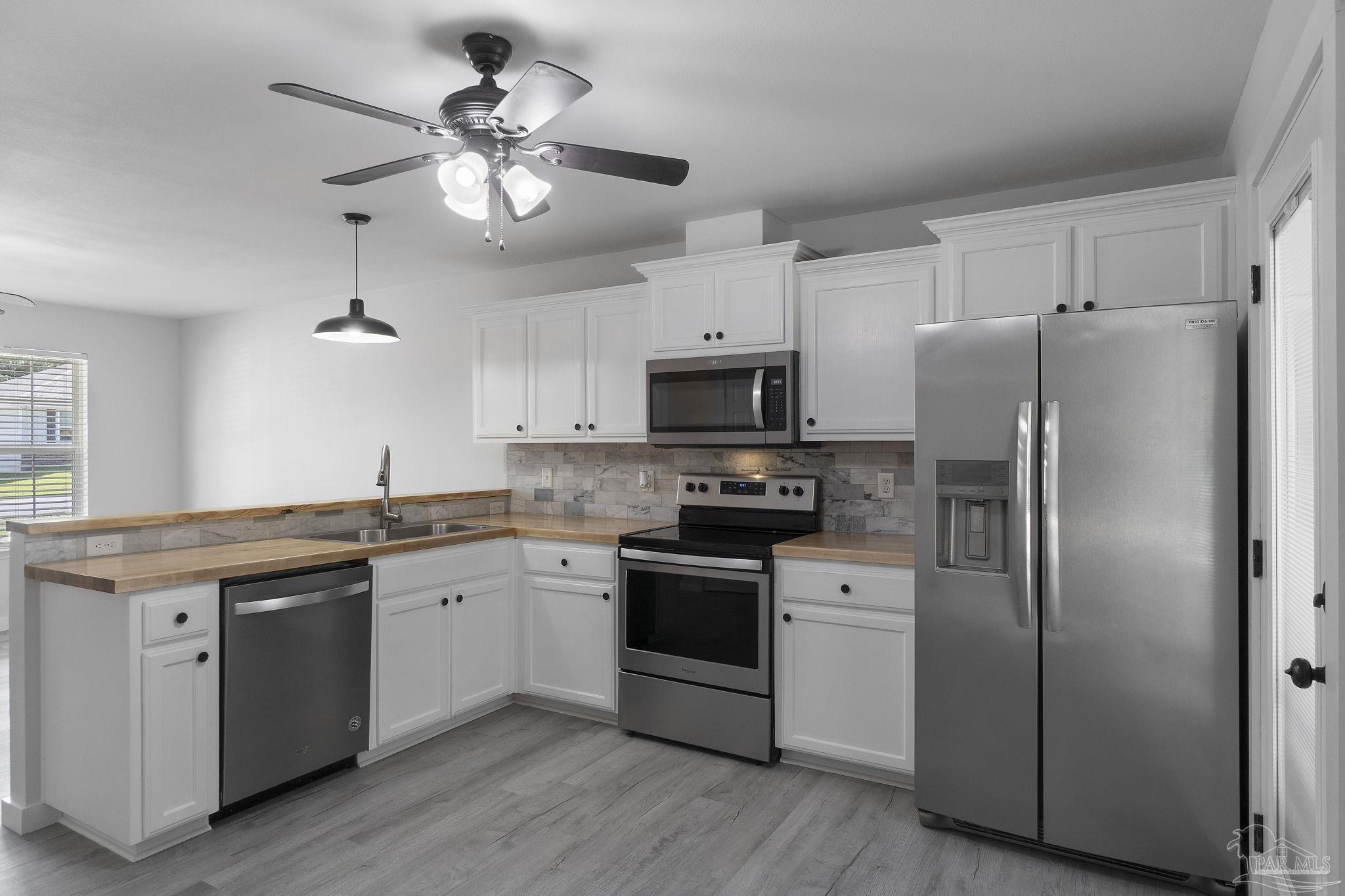 7253 Pro Lane Milton, FL 32570 - Photo 11 of 33 a kitchen with stainless steel appliances granite countertop a refrigerator a stove a sink and white cabinets