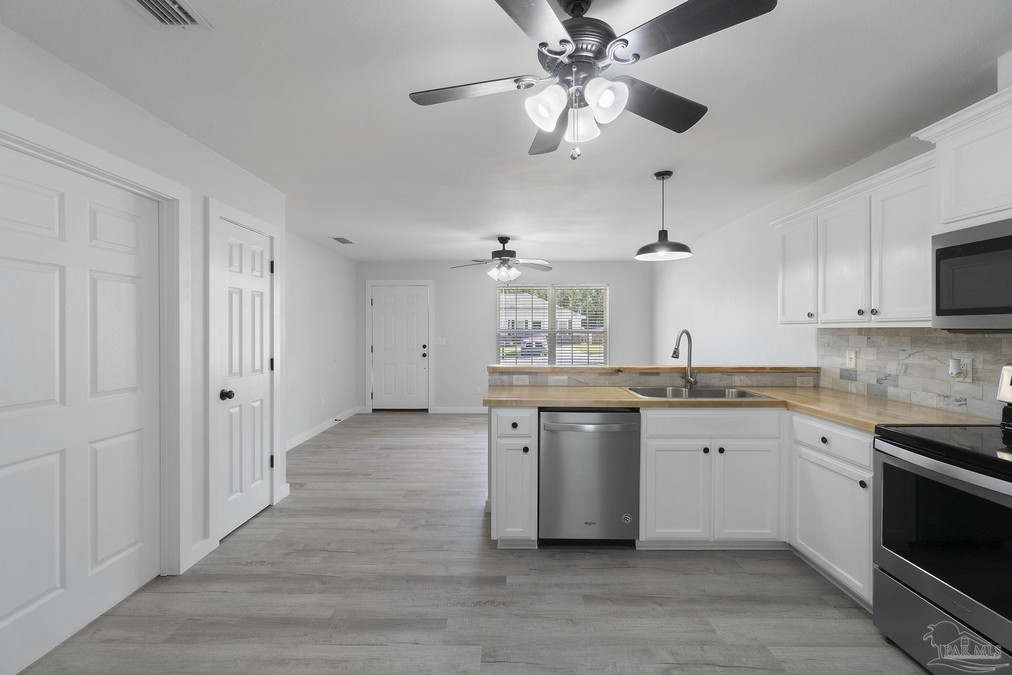 7253 Pro Lane Milton, FL 32570 - Photo 14 of 33 a kitchen with cabinets wooden floor and stainless steel appliances