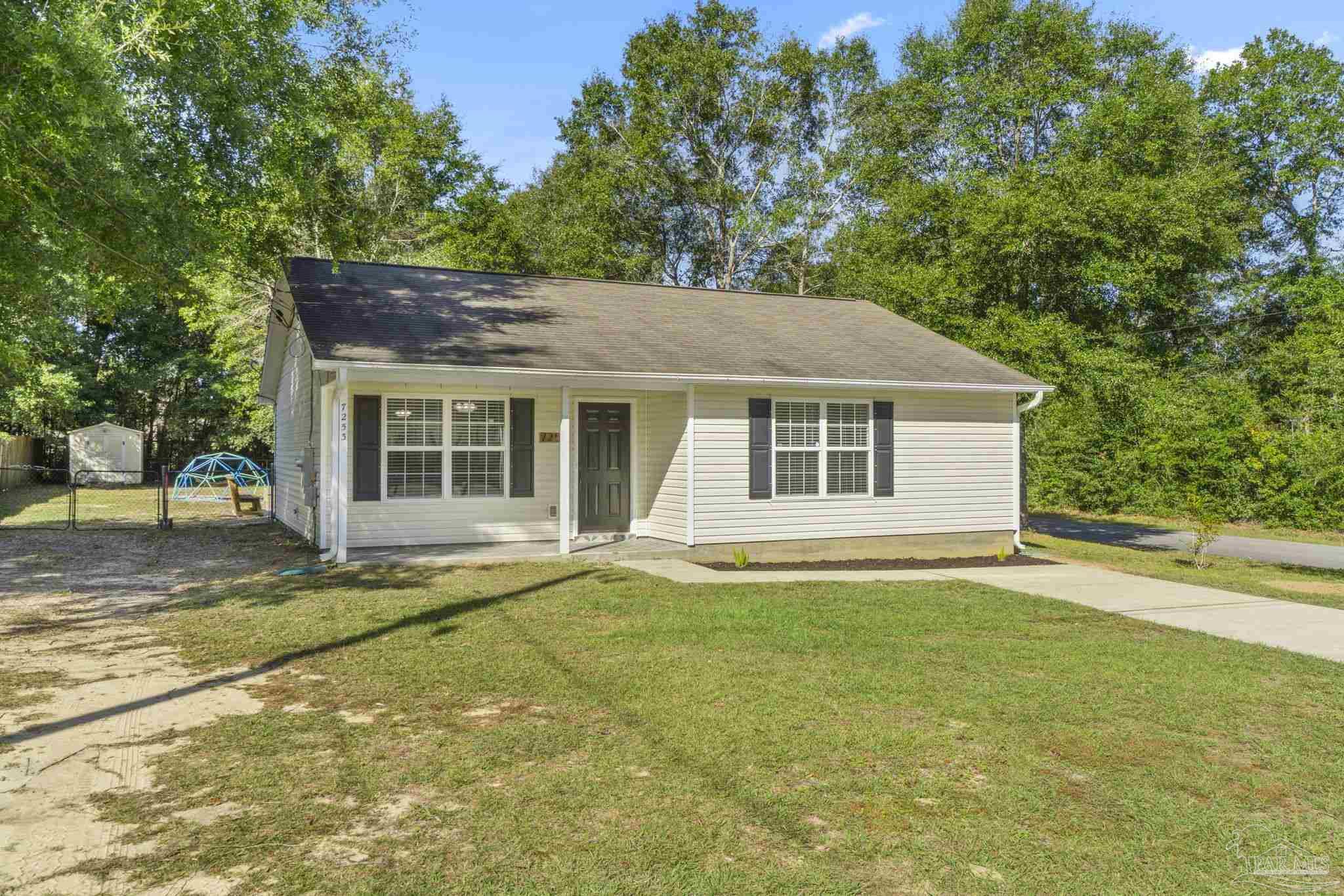 7253 Pro Lane Milton, FL 32570 - Photo 2 of 33 a front view of a house with a garden and trees