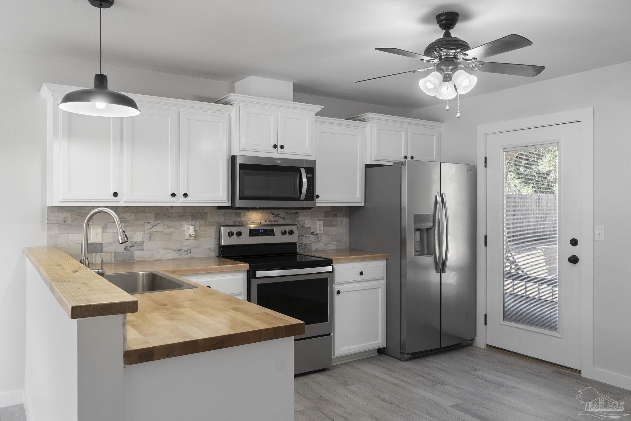 7253 Pro Lane Milton, FL 32570 - Photo 10 of 33 a kitchen with stainless steel appliances kitchen island a refrigerator sink and cabinets