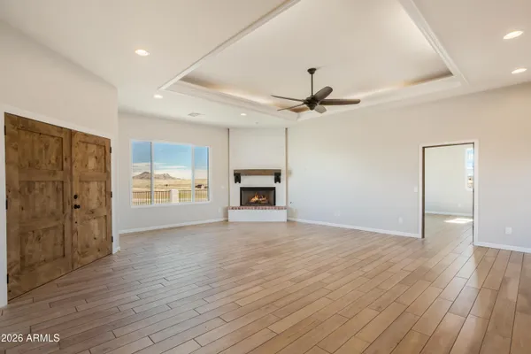 a view of an empty room with wooden floor fireplace and a window
