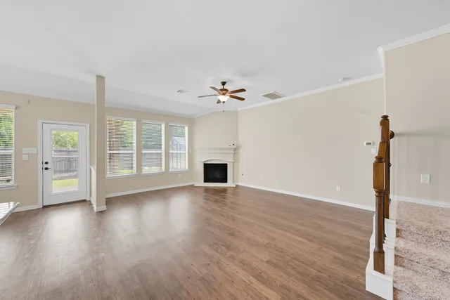 a view of an empty room with wooden floor and a fireplace