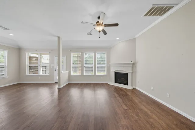 a view of an empty room with wooden floor fireplace and a window