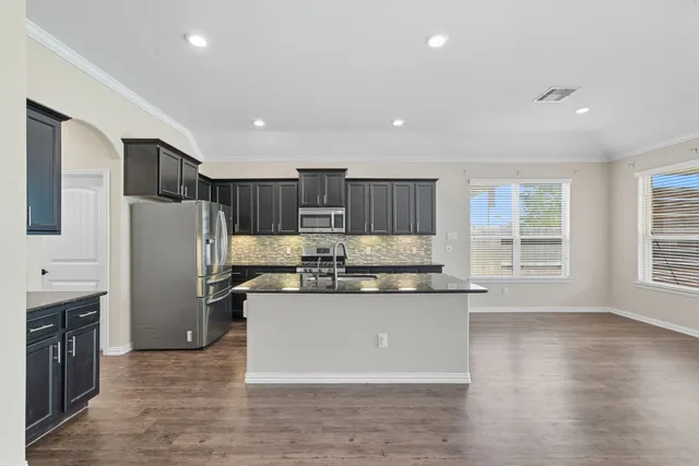 a kitchen with stainless steel appliances granite countertop a refrigerator a stove and a wooden floors