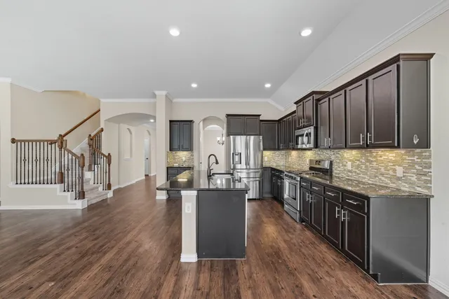 a kitchen with stainless steel appliances granite countertop wooden floors and wooden cabinets
