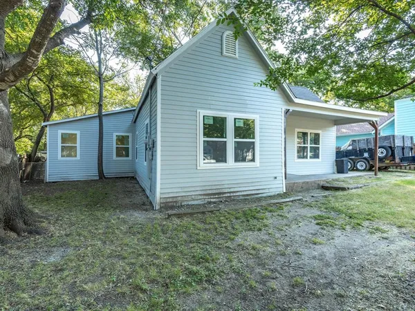 a view of a house with a yard and large trees