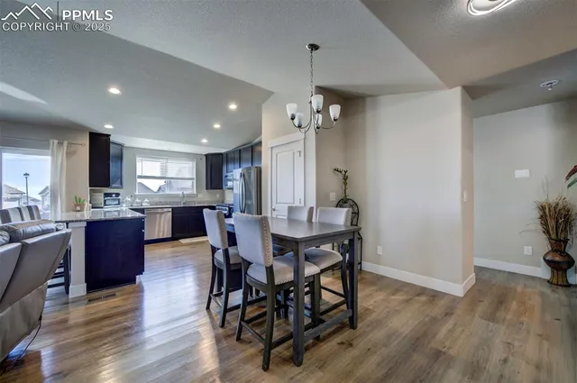 a view of a dining room and livingroom with furniture wooden floor a chandelier