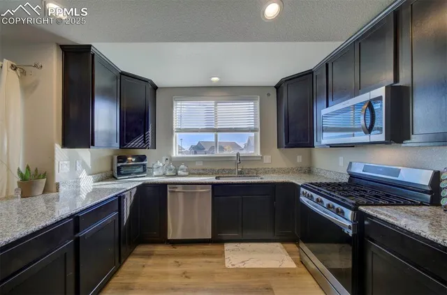 a kitchen with stainless steel appliances granite countertop a sink stove and cabinets