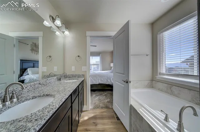 a en suite bathroom with a granite countertop tub double vanity sink and a mirror