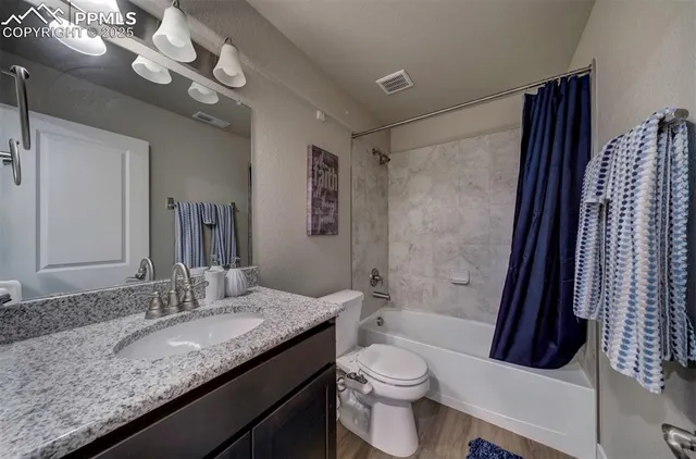 a bathroom with a granite countertop sink a toilet a mirror a bathtub and shower