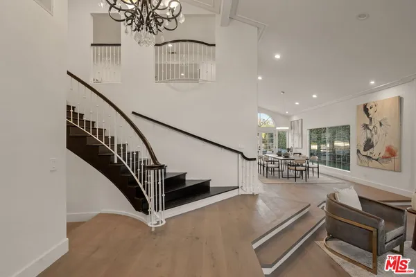 a view of entryway and hall with dining room and wooden floor