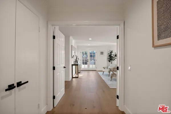 a view of a hallway with wooden floor and a living room