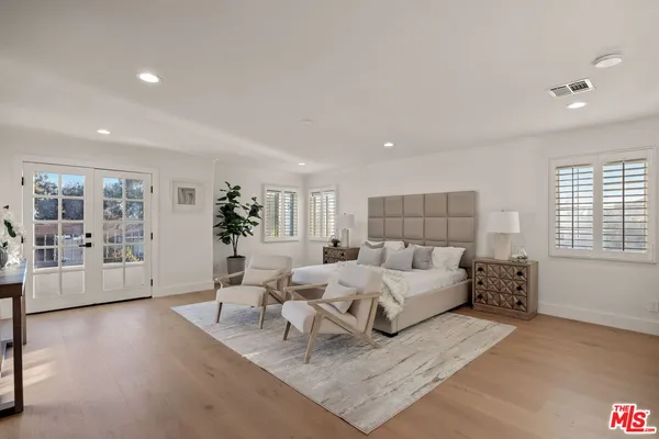 a bedroom with a large bed and potted plant with the wooden floor