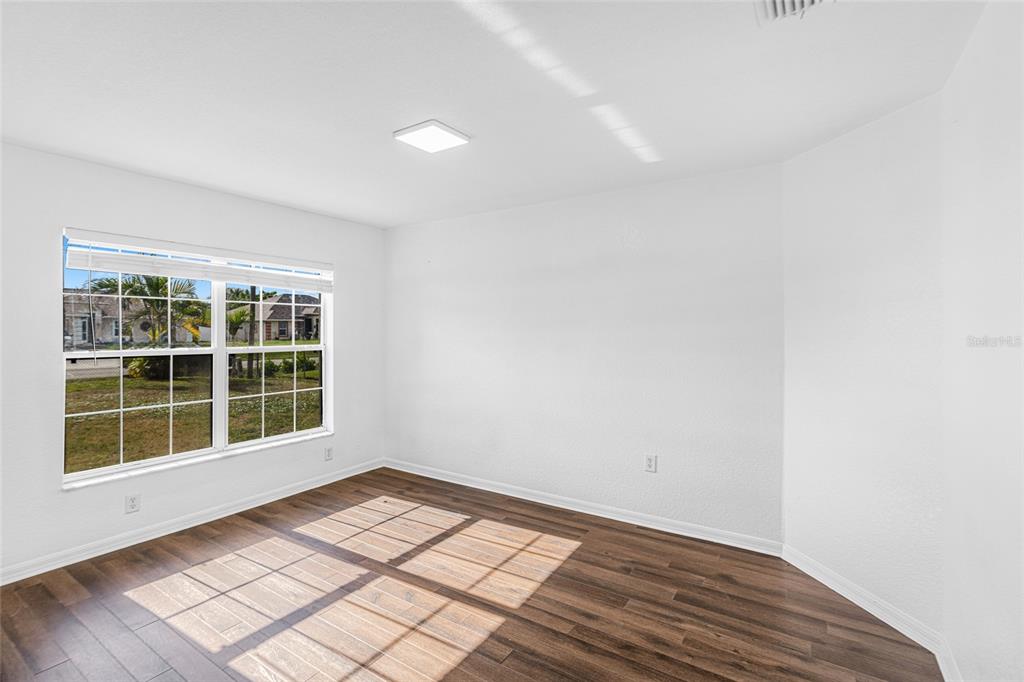 418 Windermere Drive Lehigh Acres, FL 33972 - Photo 14 of 71 a view of empty room with wooden floor and fan