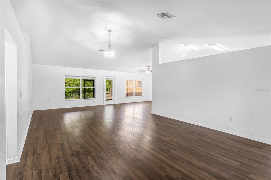 418 Windermere Drive Lehigh Acres, FL 33972 - Photo 19 of 71 an empty room with wooden floor and windows