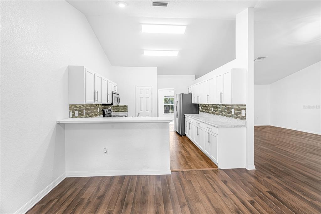 418 Windermere Drive Lehigh Acres, FL 33972 - Photo 26 of 71 a kitchen with wooden floors and white appliances