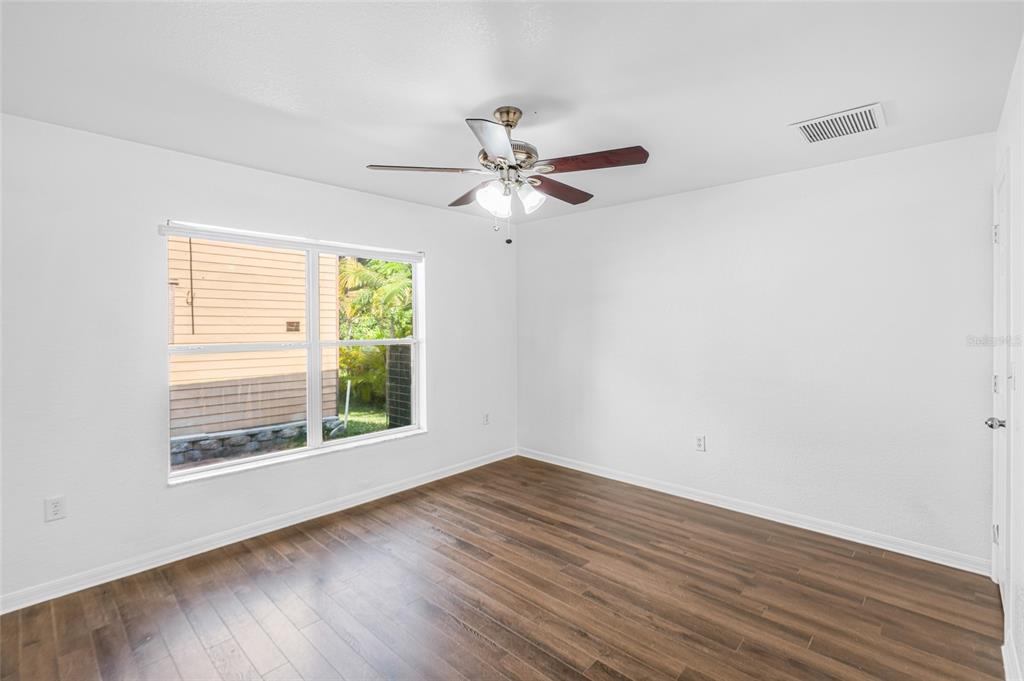 418 Windermere Drive Lehigh Acres, FL 33972 - Photo 37 of 71 an empty room with wooden floor chandelier fan and windows