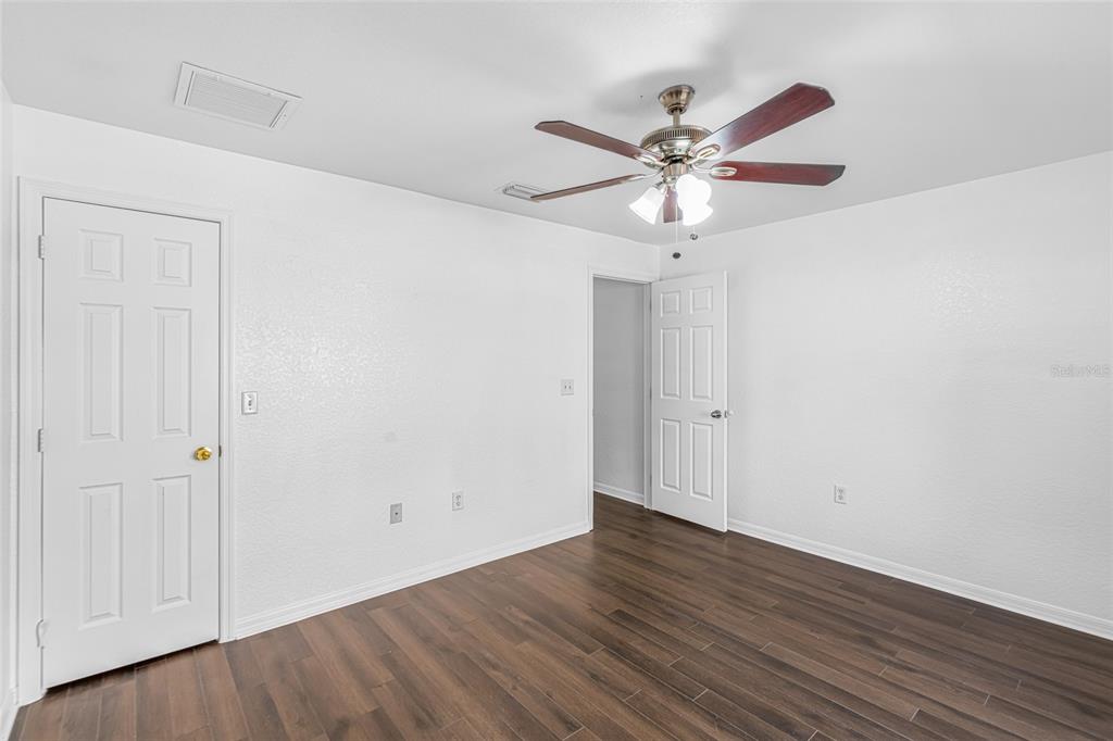 418 Windermere Drive Lehigh Acres, FL 33972 - Photo 38 of 71 a view of a room with wooden floor and a ceiling fan