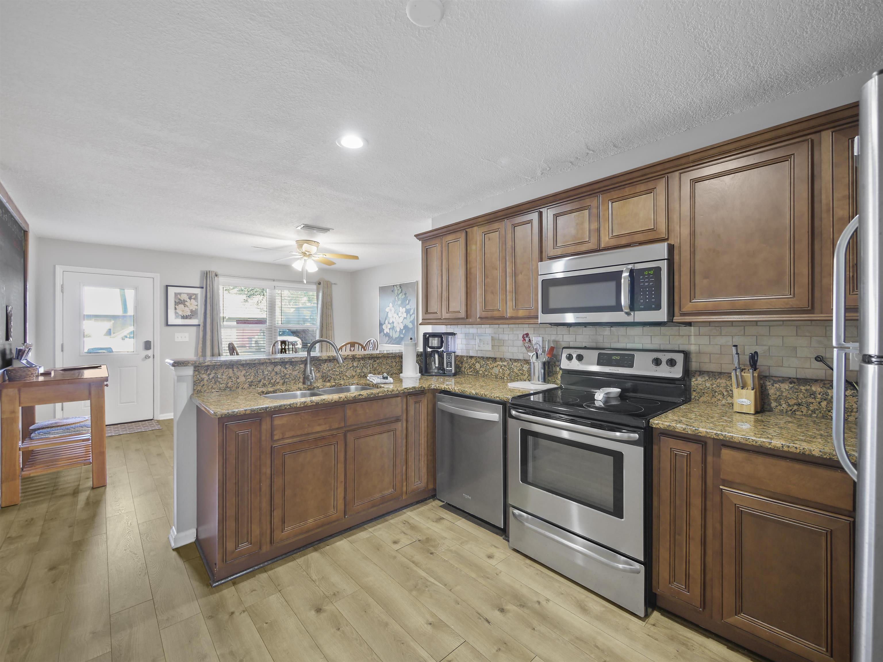 241 Tropic Way St. Augustine, FL 32080 - Photo 9 of 32 a kitchen with stainless steel appliances granite countertop a stove top oven a sink dishwasher a dining table and chairs with wooden floor