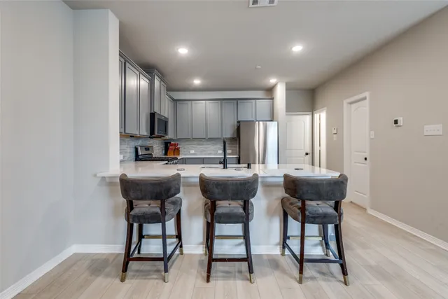 a kitchen with a dining table chairs and refrigerator