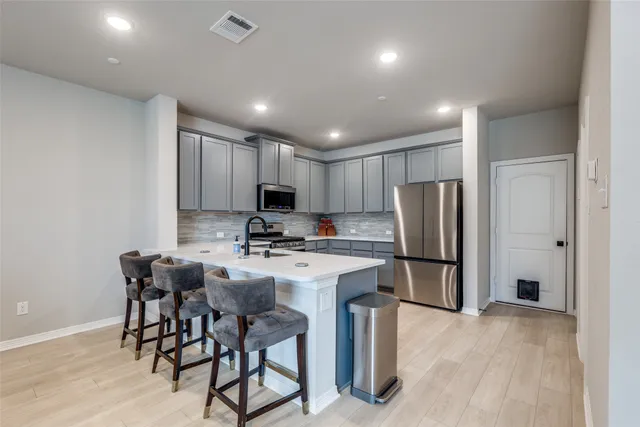 a kitchen with stainless steel appliances a refrigerator a stove a sink dishwasher with a dining table and chairs