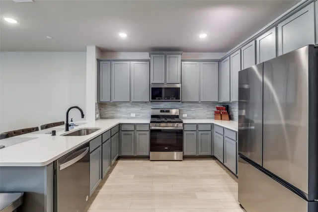a kitchen with stainless steel appliances granite countertop a refrigerator sink and stove