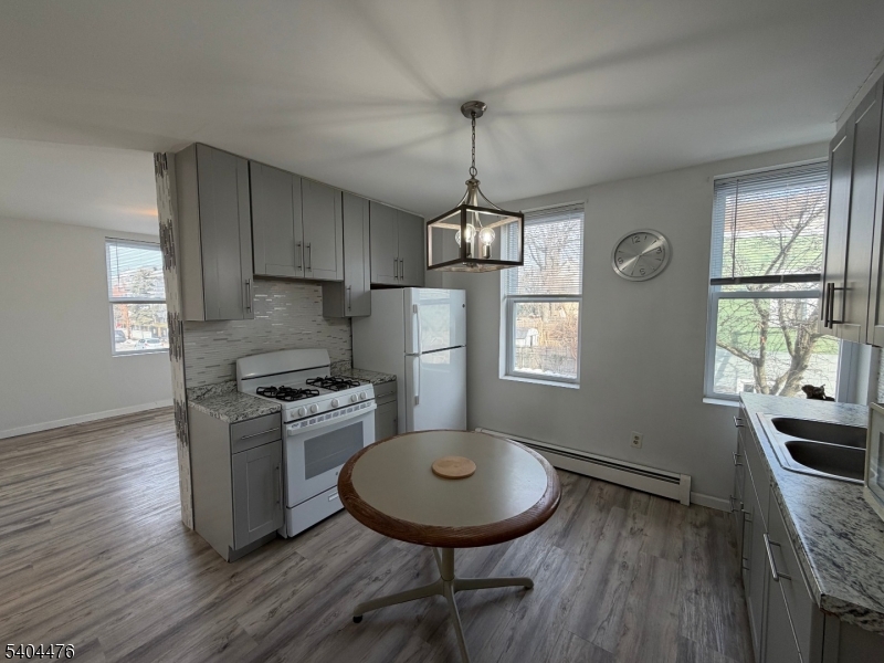 a kitchen with stainless steel appliances granite countertop a stove a refrigerator a sink dishwasher a dining table and chairs with wooden floor