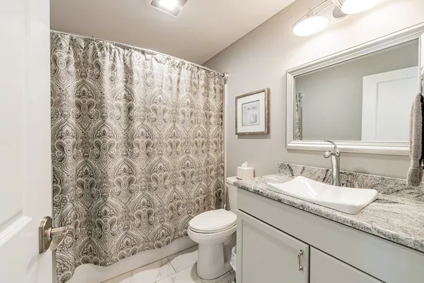 a bathroom with a granite countertop sink a toilet and a mirror
