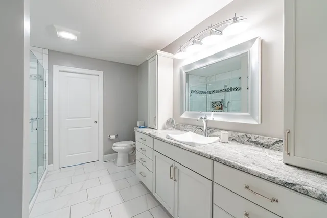 a bathroom with a granite countertop sink toilet and mirror