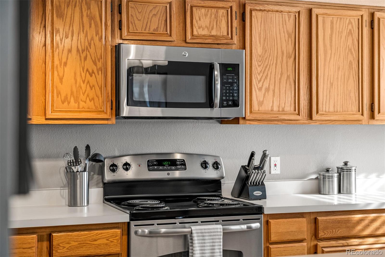 7670 Jared Way Littleton, CO 80125 - Photo 12 of 34 a kitchen with granite countertop wood cabinets and a stove top oven