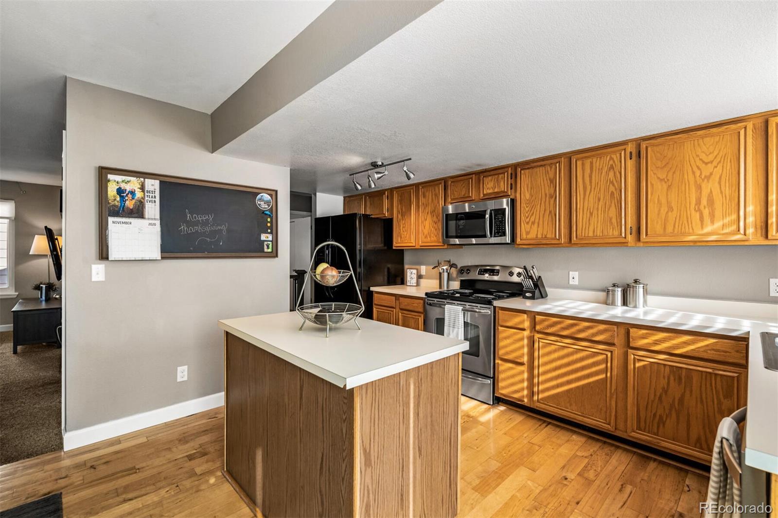 7670 Jared Way Littleton, CO 80125 - Photo 15 of 34 a kitchen with stainless steel appliances a stove top oven a sink a refrigerator white cabinets and wooden floor
