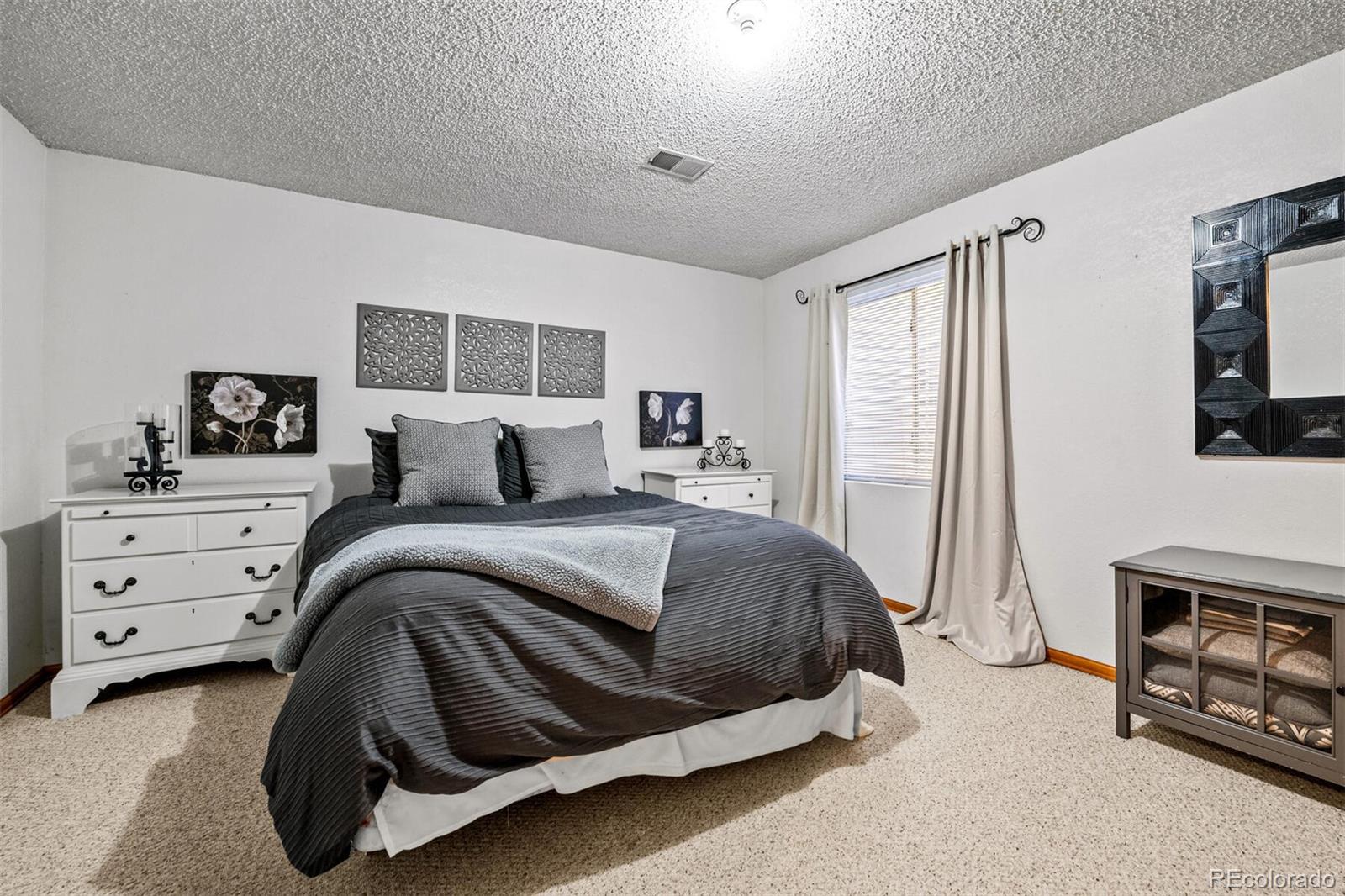 7670 Jared Way Littleton, CO 80125 - Photo 25 of 34 a bedroom with a bed a couch and dresser