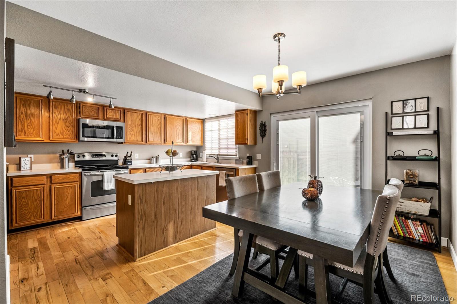 7670 Jared Way Littleton, CO 80125 - Photo 9 of 34 a kitchen with stainless steel appliances granite countertop a stove a refrigerator a kitchen island a dining table and chairs with wooden floor