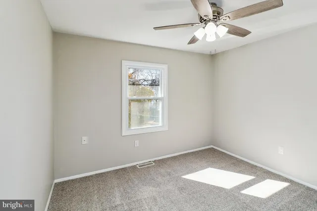 an empty room with a window and a fan