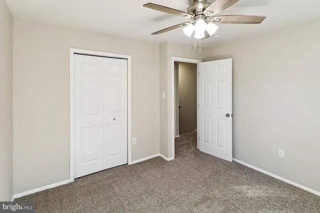 a view of an empty room and chandelier fan