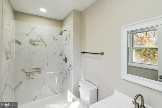 a bathroom with a bathtub shower and toilet