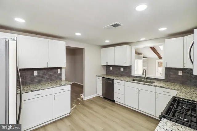 a kitchen with granite countertop white cabinets and white appliances