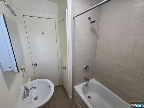 a bathroom with a tub shower and sink
